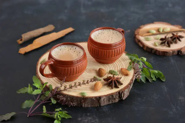 Top view of Indian herbal Masala Chai or traditional beverage tea with milk and spices Kerala India. Two cups of organic ayurvedic or herbal drink India, good in winter for immunity boosting.