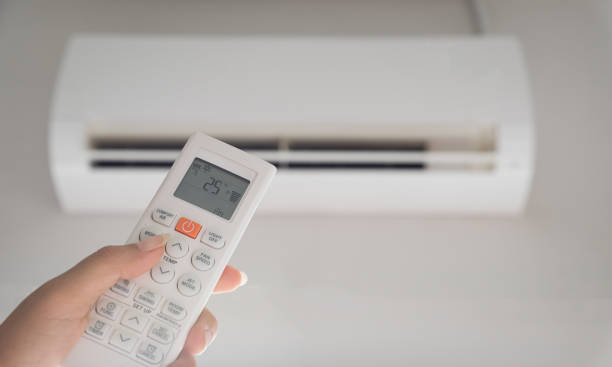 istock Hand holding remote controller directed on the air conditioner inside the room and set at ambient temperature,25 degrees celsius. 1336602926