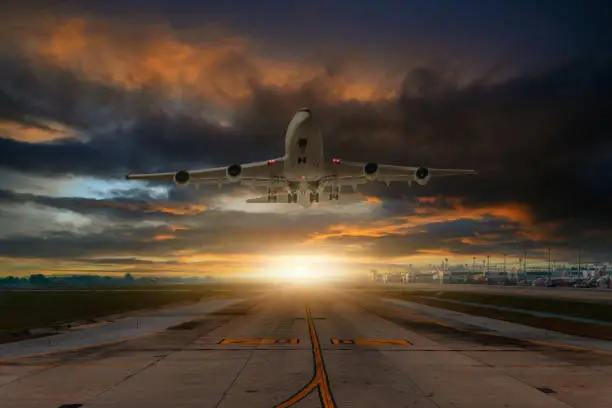 Airplane passenger or cargoplane is take off flying away go to high altitude during sunset time sky background.
