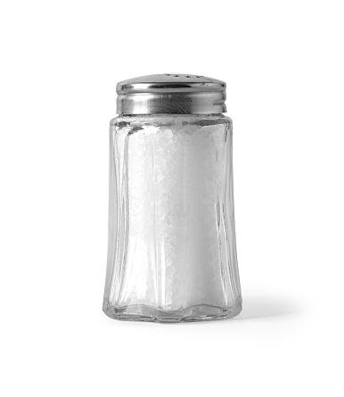 Hand is holding salt shaker with salt on soft black background.