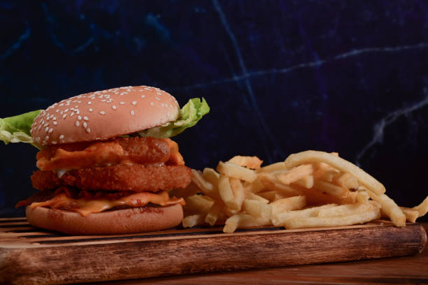 istock Tasty crispy fish burger and fried potatoes on wooden table. 1336610973