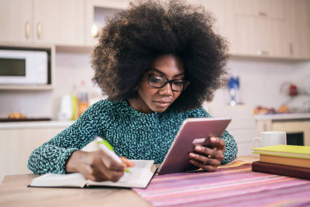 istock African american young woman working from home. Student girl using notepad in her kitchen stock photo 1336614670