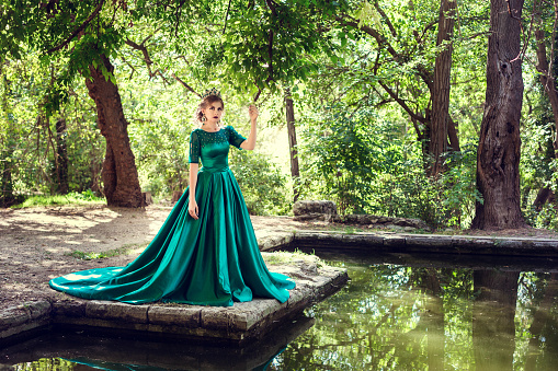 Young woman wearing a green dress explores a magical forest. The idea and concept of fairy tales, magic.