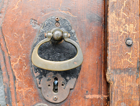 Vintage metal door knocker on wooden surface.