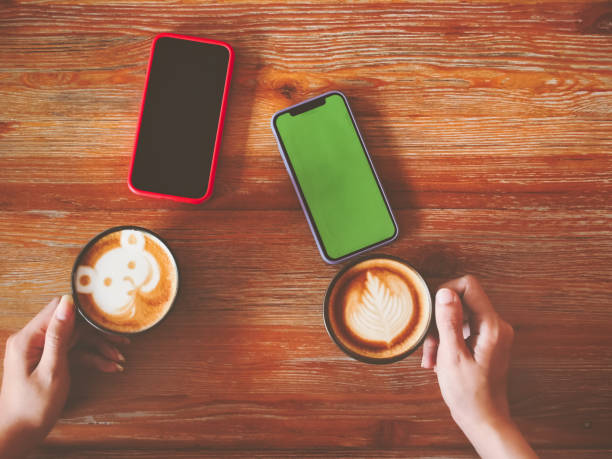 woman hold mockup smart phone mobile green screen and drinking coffee in coffee shop or cafe.