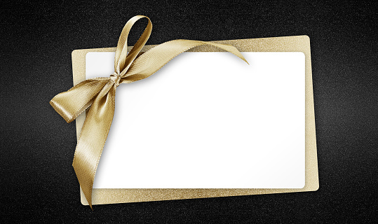 White gift card with golden ribbon bow, isolated on black background template with copy space for promotional offer, black friday concept