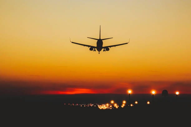 飛行機は、日没と夜の間に滑走路に着陸 - airport airplane landing red ストックフォトと画像
