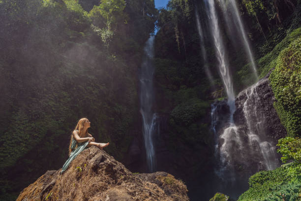 mujer vestida de color turquesa en las cascadas de sekumpul en las selvas de la isla de bali, indonesia. concepto de viaje de bali - waterfall river stream mountain fotografías e imágenes de stock