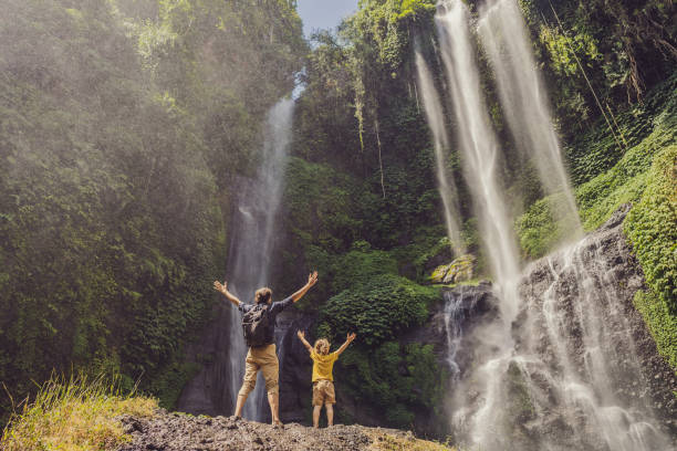 papá e hijo en las cascadas de sekumpul en las selvas de la isla de bali, indonesia. concepto de viaje de bali - waterfall river stream mountain fotografías e imágenes de stock