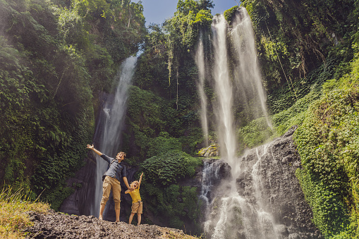 Dad and son at the Sekumpul waterfalls in jungles on Bali island, Indonesia. Bali Travel Concept.