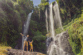 Dad and son at the Sekumpul waterfalls in jungles on Bali island, Indonesia. Bali Travel Concept