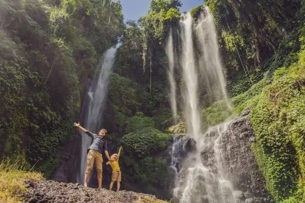 Photo of Dad and son at the Sekumpul waterfalls in jungles on Bali island, Indonesia. Bali Travel Concept