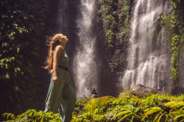 mujer vestida de color turquesa en las cascadas de sekumpul en las selvas de la isla de bali, indonesia. concepto de viaje de bali - stream forest river waterfall fotografías e imágenes de stock