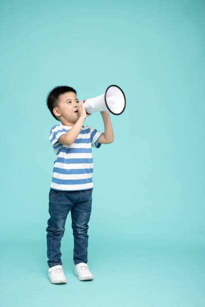 緑の背景に隔離されたメガホンを保持しているアジアの小さな男の子、スピーチと発表コンセプト - one little boy audio ストックフォトと画像