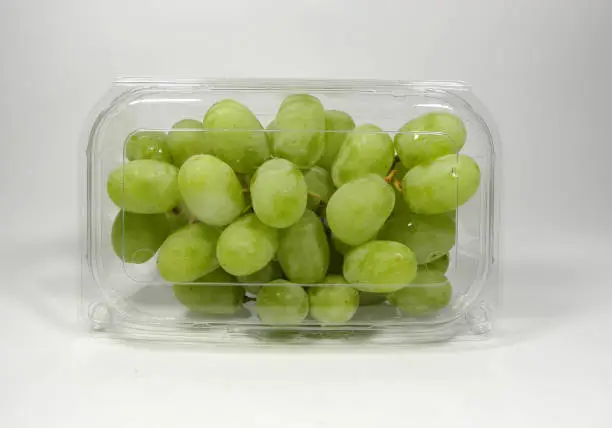 Photo of A box of American seedless green grapes packed in a transparent plastic box, on a white background