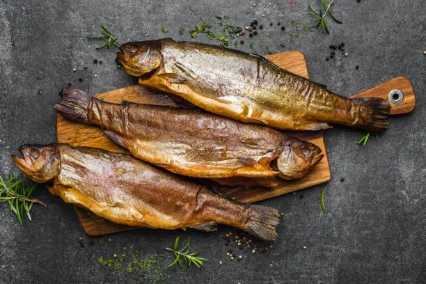 Smoked fish with spices on dark background