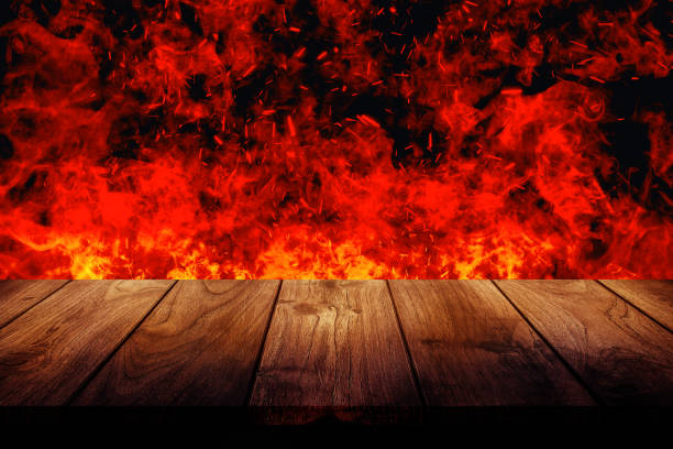istock Empty wooden table top with orange fire or flame and sparkles in dark room. 1336634709