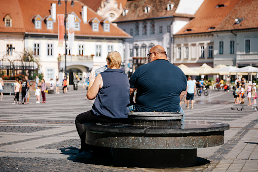 Sibiu, Romania - 19 August, 2021: rear view of an obese man sitting down outdoors in a public square in Sibiu, Romania.