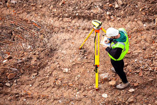 A surveyor on a construction site uses an optical level