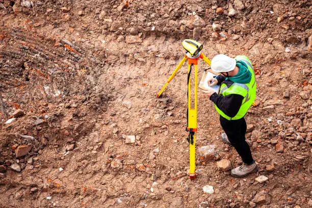 Photo of A surveyor on a construction site uses an optical level
