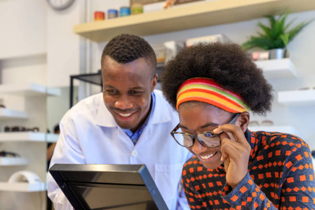 óptica africana explicando e vendendo óculos para jovem cliente em loja de lojas ópticas. conceito de cuidados oculares. - optometrist store retail glasses - fotografias e filmes do acervo