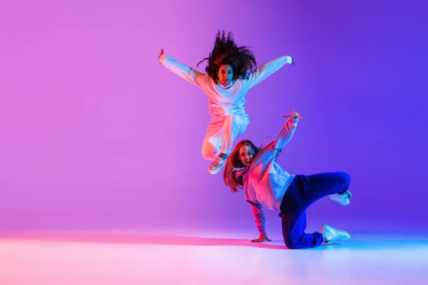 istock Two active young girls dancing hip-hop on gradient pink purple neon studio background 1336641097