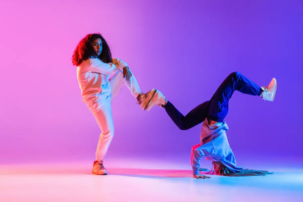 istock Two beautiful young girls dancing hip-hop dynamically on colorful gradient background in neon. 1336641118