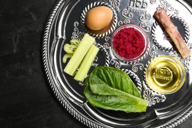 Passover Seder plate (keara) on black table, top view. Pesah celebration