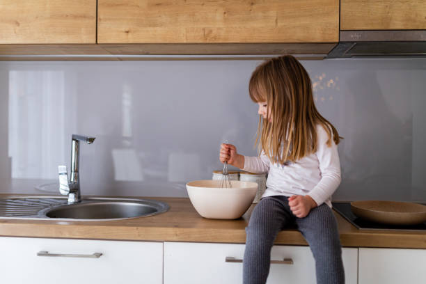 istock Little girl cooking while sitting on kitchen counter 1336641225