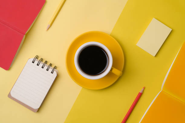 istock Coffee cup, notebooks and pencils on yellow background. 1336641772