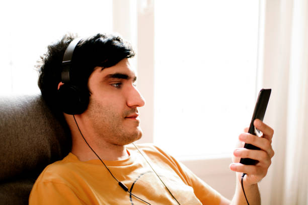 istock man sitting by the window looking at the phone 1336641918