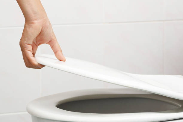 man's hand opening the toilet lid
