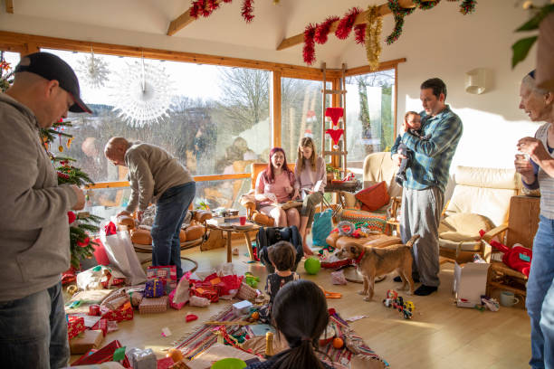 Christmas Surprises! A shot of a family sitting with their Christmas gifts on Christmas Day, they are sitting together around the living room which is decorated in Christmas Decorations. 12 17 months stock pictures, royalty-free photos & images
