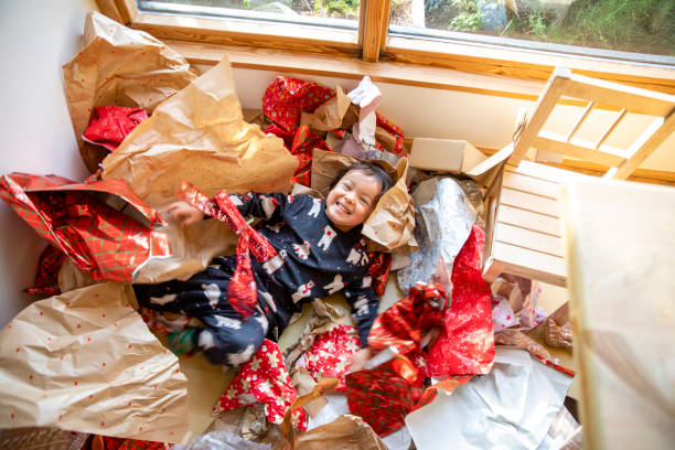 Best Christmas Ever! A shot of a young boy laying in all his Christmas wrapping paper, He is looking up at the camera with a smile, feeling grateful for all his Christmas presents. unwrapping stock pictures, royalty-free photos & images