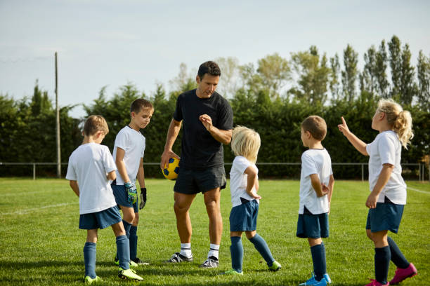 istock Male coach explaining about soccer to kids at field 1336646253