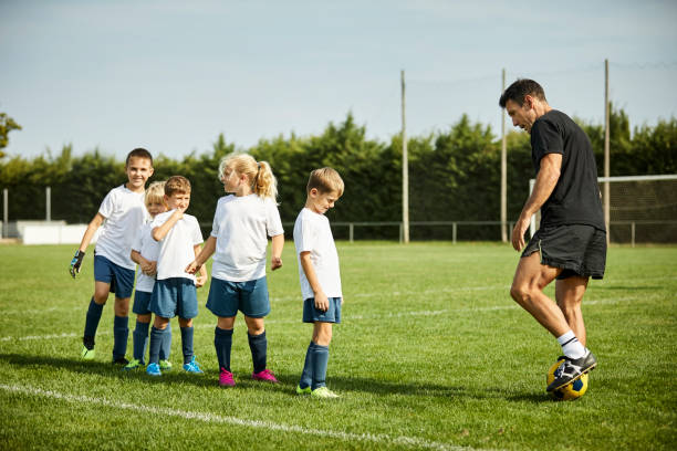 istock Male coach teaching soccer to kids on grass 1336646254