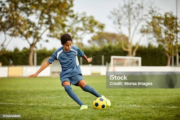 Teenage Boy Kicking Soccer Ball In Field Stock Photo - Download Image Now - Soccer, Soccer Ball, Teenage Boys