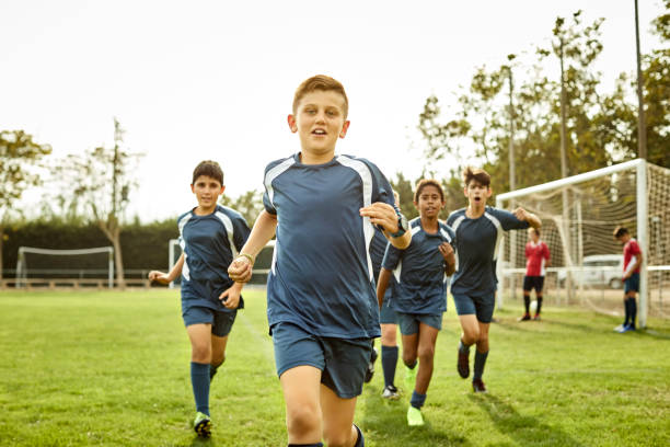 porträt von teenagern, die auf dem fußballplatz laufen - sports uniform stock-fotos und bilder