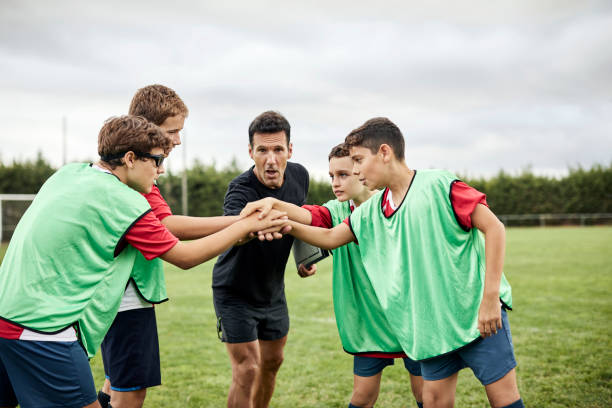 istock Portrait of coach with team stacking hands in field 1336647130