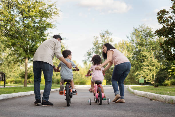 Parents teaching their little child to ride a bike stock photo