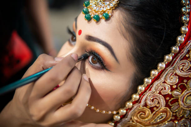 schöne traditionelle indische braut bereitet sich auf ihren hochzeitstag durch make-up-artist vor. schöne traditionelle indische braut bereitet sich auf ihren hochzeitstag durch make-up-artist vor. - women bride personal accessory adult stock-fotos und bilder