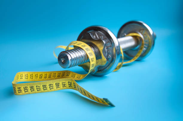 istock Yellow tape on dumbbell on blue background 1336650194