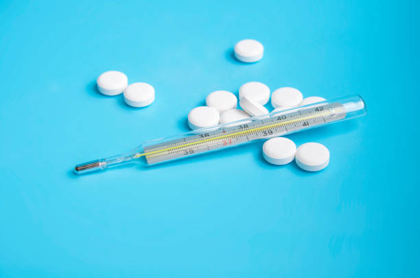 istock thermometer and white pills on the blue background 1336651733