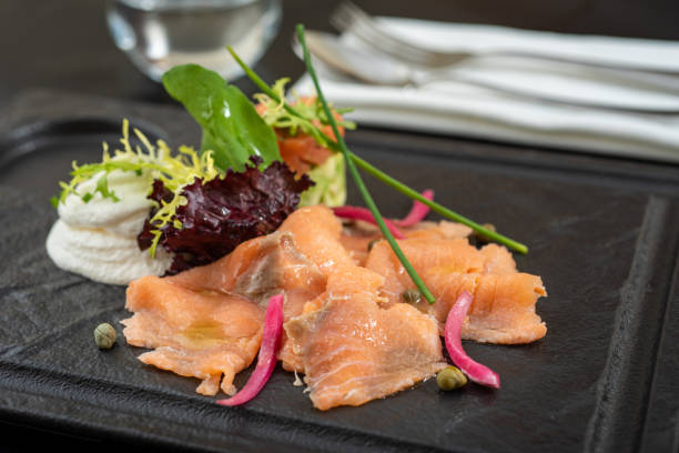 istock Smoked salmon with cream cheese and salad on a black stone plate. 1336654452