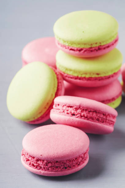 istock Pink green macaroons cakes on gray blue table background, place for text, trendy minimalism style, selective focus 1336654634