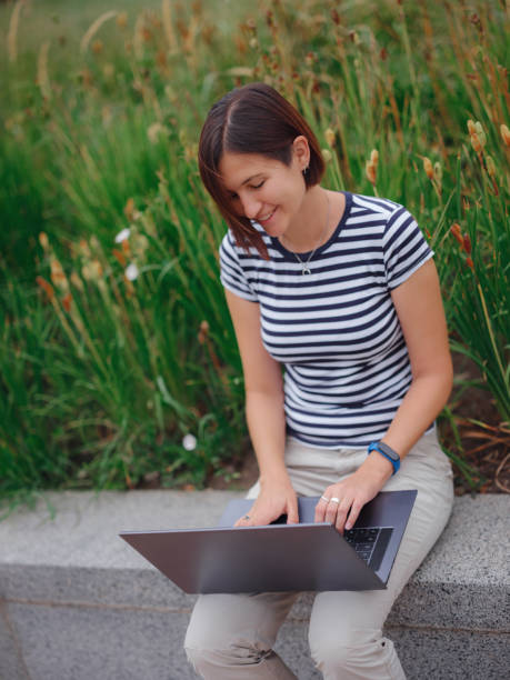 istock woman working with laptop in modern university campus park. 1336655297