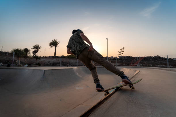 il giovane skater fa un trucco chiamato "rock to fakie" sul bordo di una piscina al tramonto - fakie foto e immagini stock