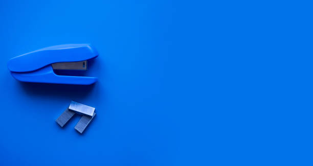 Blue stapler and staples on a blue background. Stationery. Place for your text.