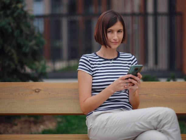 istock Smiling woman using mobile phone in the street 1336656619