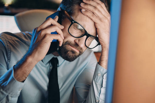 istock Frustrated young man talking on mobile phone and keeping eyes closed 1336658012